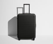 Front product view of The Medium suitcase in Jet Black with raised handle