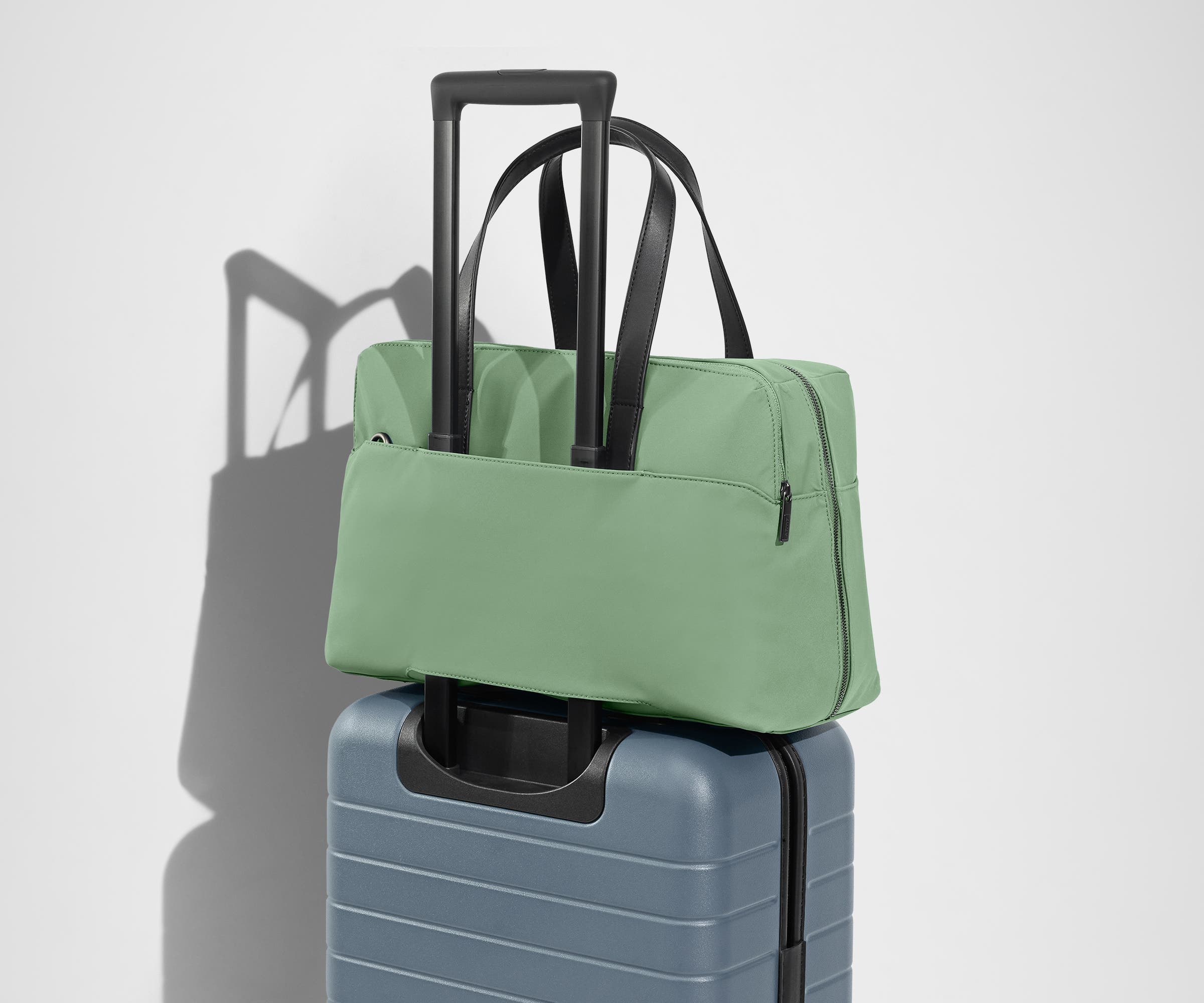 The Everywhere Bag secured to an Away suitcase by its trolley sleeve