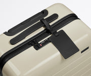 The Carry-On suitcase in Coast Blue shown shown from above highlighting TSA-approved combination lock and recycled leather luggage tag