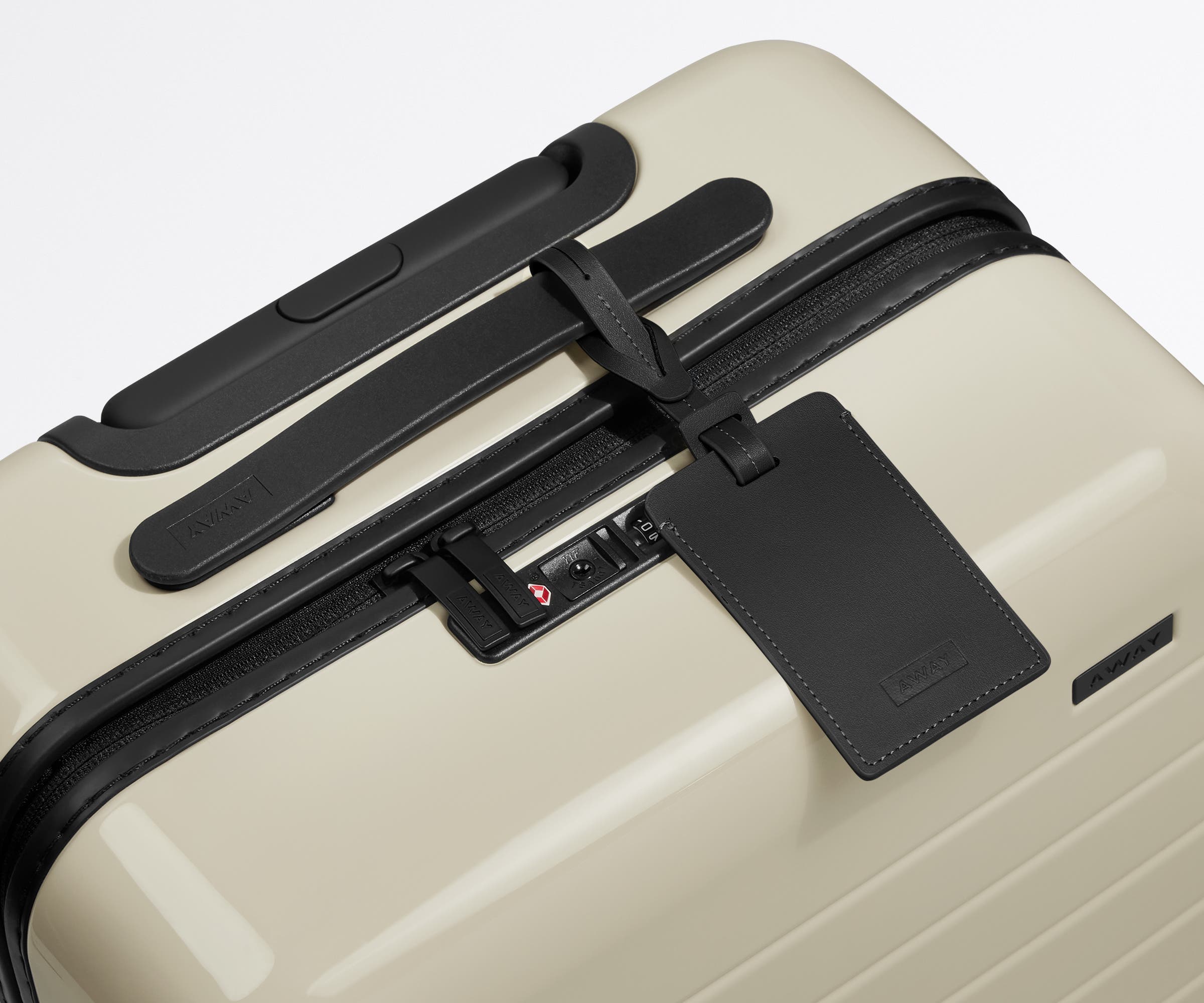 The Carry-On suitcase in Coast Blue shown shown from above highlighting TSA-approved combination lock and recycled leather luggage tag